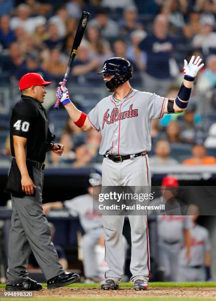 Tyler Flowers of the Atlanta Braves talks with umpire Roberto Ortiz as reacts while batting in an interleague MLB baseball game against the New York...