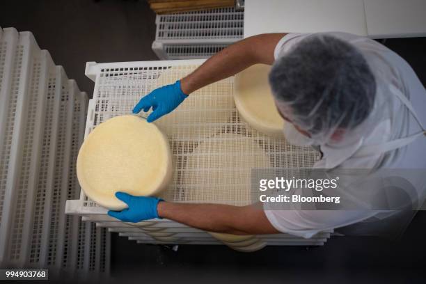 An employee places San Geronimo cheese wheels on a rack to dry at the Nicasio Valley Cheese Co. Facility in Nicasio, California, U.S., on Friday,...
