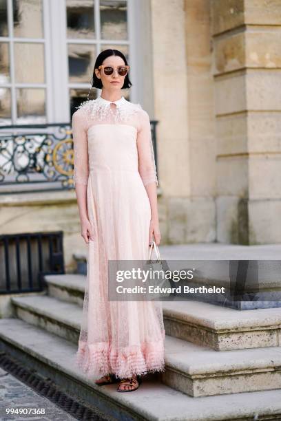 Erin O'Connor wears a pink lace mesh dress, sunglasses, a white bag , outside Dior, during Paris Fashion Week Haute Couture Fall Winter 2018/2019, on...