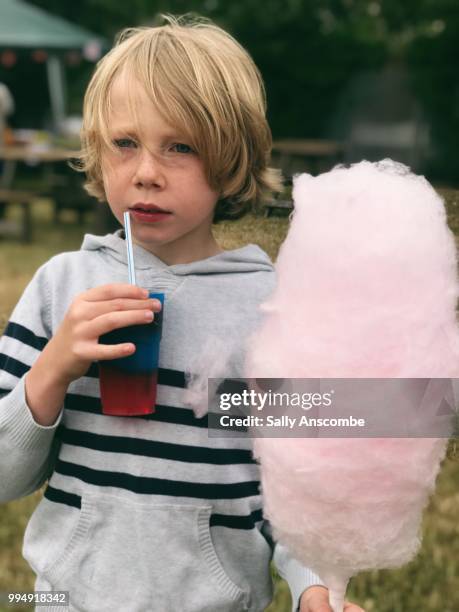 child holding a candy floss and a slushy drink - sally anscombe stock-fotos und bilder