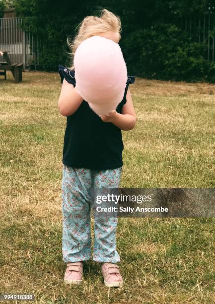 chid eating a candy floss - sally anscombe stock-fotos und bilder