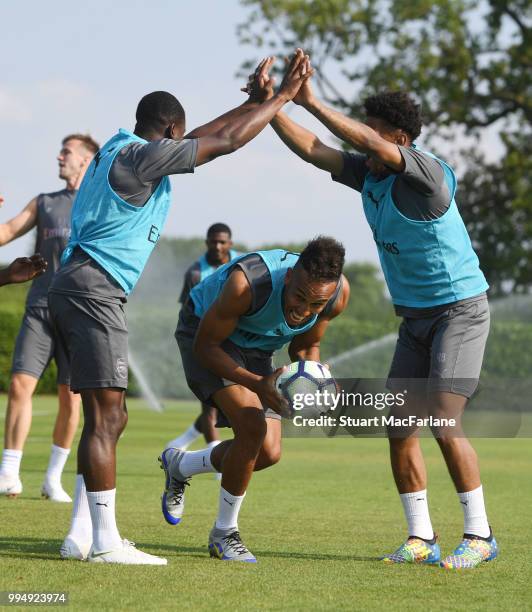Alex Lacazette, Pierre-Emerick Aubameyang and Reiss Nelson of Arsenal share a joke during a training session at London Colney on July 9, 2018 in St...