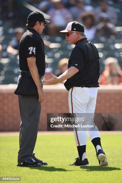 Manager Buck Showalter of the Baltimore Orioles talks with umpire John Tumpane during a game one of a doubleheader baseball game against the...