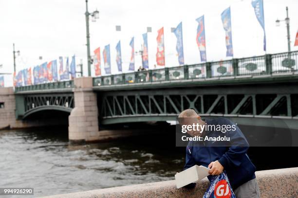 Man looks his laptop along the Neva River in Saint Petersburg, Russia on July 09, 2018.