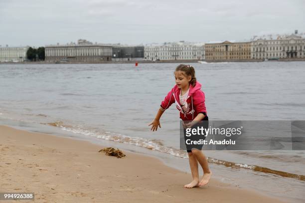 Girl plays with sand along the Neva River in Saint Petersburg, Russia on July 09, 2018.