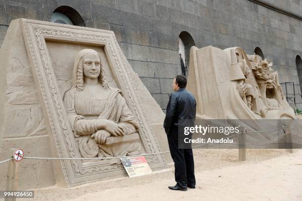 Man views a sand sculpture of Leonardo Da Vinci's Mona Lisa, along the Neva River in Saint Petersburg, Russia on July 09, 2018.