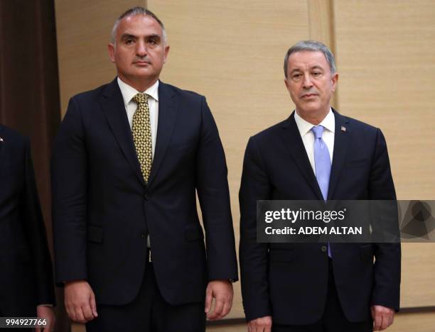 Turkey's newly appointed Culture and Tourism Minister Mehmet Ersoy and newly appointed Defence Minister Hulusi Akar look on during the presentation...