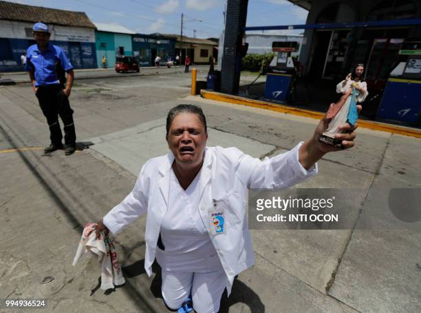 Woman kneels holding a religious figure as a caravan of the Catholic Church, including cardinal Leopoldo Brenes, passes by in Diriamba, Nicaragua, on...
