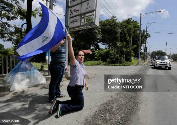 Woman kneels waving a Nicaraguan flag as faithfuls welcome a caravan of the Catholic Church, including cardinal Leopoldo Brenes, in Diriamba,...