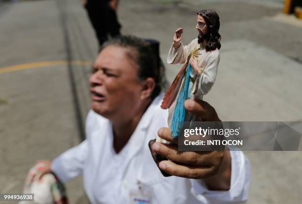 Woman kneels holding a religious figure as a caravan of the Catholic Church, including cardinal Leopoldo Brenes, passes by in Diriamba, Nicaragua, on...