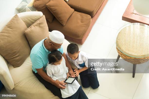 資深穆斯林男子與他的孫子使用電子閱讀器 - e reader 個照片及圖片檔