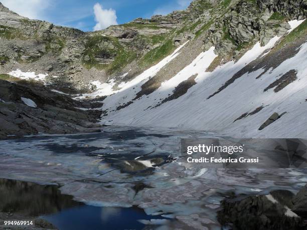 partly frozen upper paione lake (lago del paione superiore), bognanco valley - lepontinische alpen stock-fotos und bilder