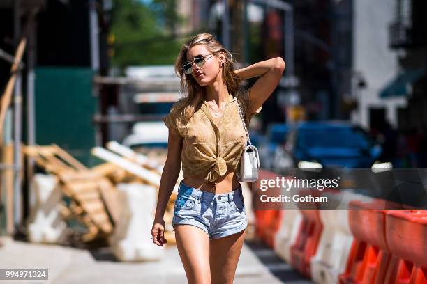 Joy Corrigan is seen wearing a Chasing Unicorns top, One Teaspoon jean shorts with Buffalo London sneakers in the Lower East Side on July 9, 2018 in...