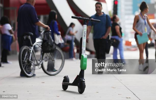 Lime dockless electric scooter is parked on a Wilshire Boulevard sidewalk, available for its next rider, on July 9, 2018 in Los Angeles, California....