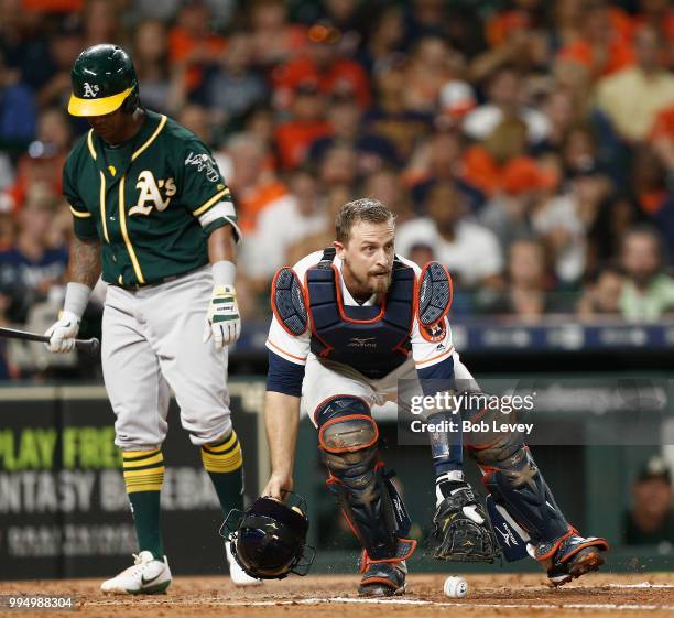 Tim Federowicz of the Houston Astros tracks down a loose ball as Khris Davis of the Oakland Athletics stands in the batters box at Minute Maid Park...