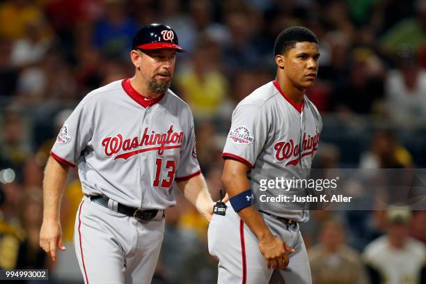 Third base coach Bob Henley walks Juan Soto of the Washington Nationals off the field after striking out in the seventh inning against the Pittsburgh...