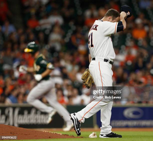 Brad Peacock of the Houston Astros wipes his forehead as Stephen Piscotty of the Oakland Athletics rounds the bases after hitting a home run i the...