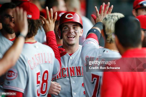 Scooter Gennett of the Cincinnati Reds gets congratulations in the dugout after scoring against the Cleveland Indians during the fourth inning at...