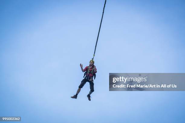 Members of the rope jump french team Pyrenaline jump from atop the rugged rocks overlooking the azure waters, Ionian Islands, Zakynthos, Greece.