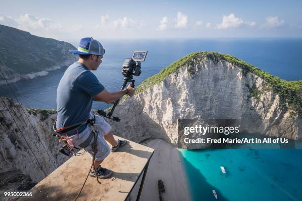 YouTube star director Devin Supertramp shooting members of the rope jump french team Pyrenaline jump from atop the rugged rocks overlooking the azure...