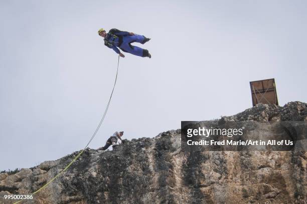 Members of the rope jump french team Pyrenaline jump from atop the rugged rocks overlooking the azure waters, Ionian Islands, Zakynthos, Greece.