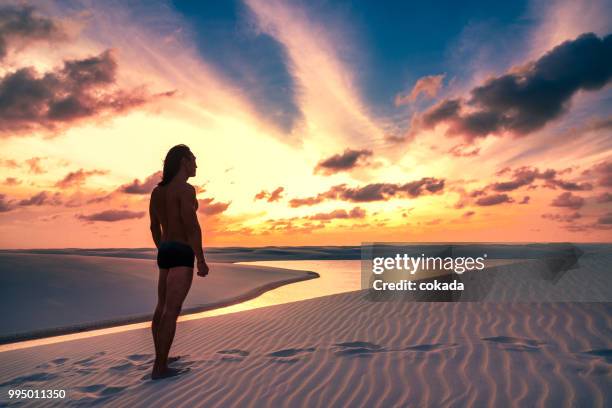 jovem homem musculoso nas areias do lençois maranhenses assistindo o pôr do sol - estado do maranhão - fotografias e filmes do acervo