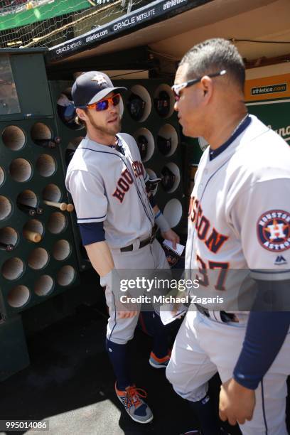 Josh Reddick and First Base Coach Alex Cintron of the Houston Astros talk in the dugout prior to the game against the Oakland Athletics at the...