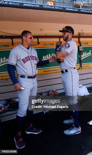 First Base Coach Alex Cintron and Carlos Correa of the Houston Astros talk in the dugout prior to the game against the Oakland Athletics at the...