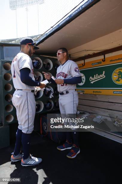 Carlos Correa and First Base Coach Alex Cintron of the Houston Astros talk in the dugout prior to the game against the Oakland Athletics at the...