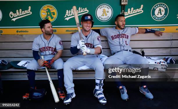 Jose Altuve, Alex Bregman and Carlos Correa of the Houston Astros relax in the dugout prior to the game against the Oakland Athletics at the Oakland...