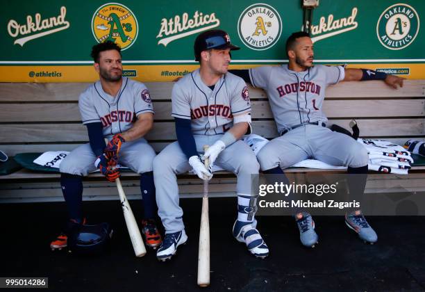Jose Altuve, Alex Bregman and Carlos Correa of the Houston Astros relax in the dugout prior to the game against the Oakland Athletics at the Oakland...