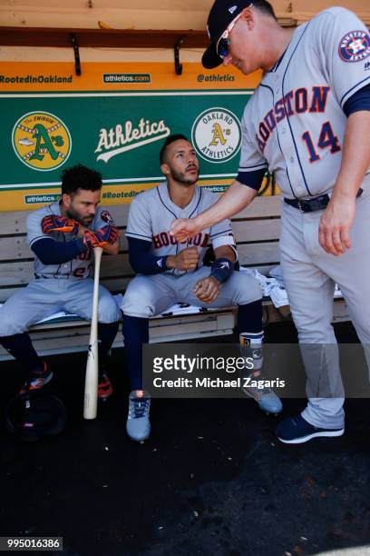Jose Altuve, Carlos Correa and Manager AJ Hinch of the Houston Astros bump fist in the dugout prior to the game against the Oakland Athletics at the...