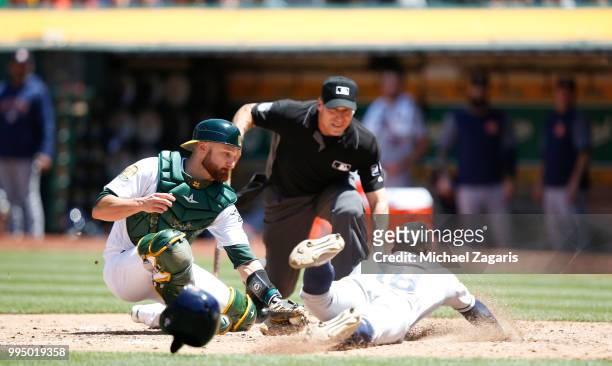 Tony Kemp of the Houston Astros beats the tag at home by Jonathan Lucroy of the Oakland Athletics during the game at the Oakland Alameda Coliseum on...