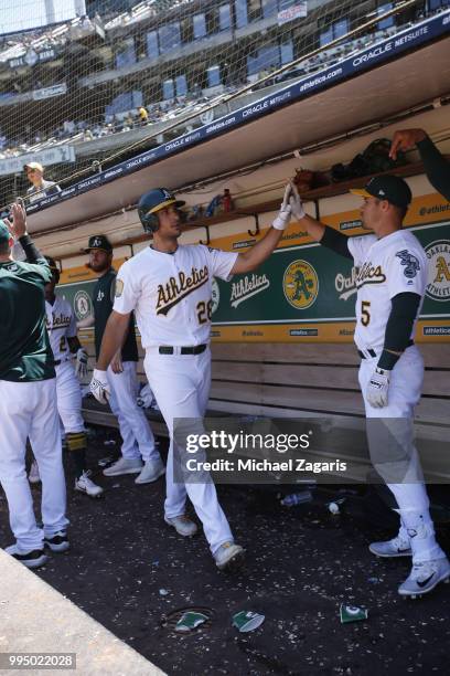 Matt Olson of the Oakland Athletics is congratulated in the dugout by Jake Smolinski after hitting a home run during the game against the Houston...