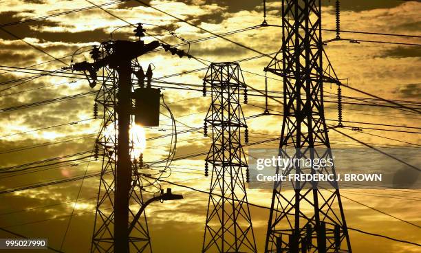 The sun sets behind power lines and poles in Rosemead, California, on July 9, 2018. While temperatures have dropped slightly from the record heatwave...