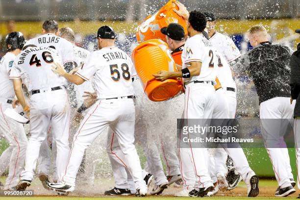 The Miami Marlins celebrate after Bryan Holaday of the Miami Marlins hit a walk-off single in the tenth inning against the Milwaukee Brewers at...