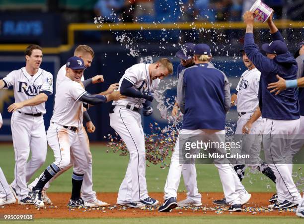 Daniel Robertson, center, of the Tampa Bay Rays is congratulated on his game-winning hit in the 10th inning of a baseball game at Tropicana Field on...