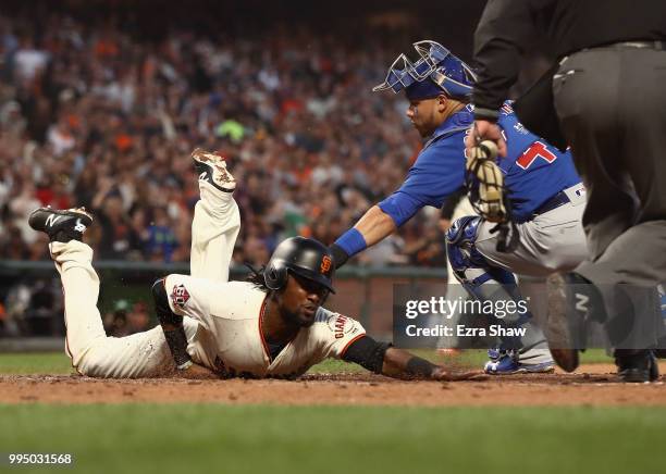 Alen Hanson of the San Francisco Giants beats the tag of Willson Contreras of the Chicago Cubs to score after a failed pick off attempt in the fifth...