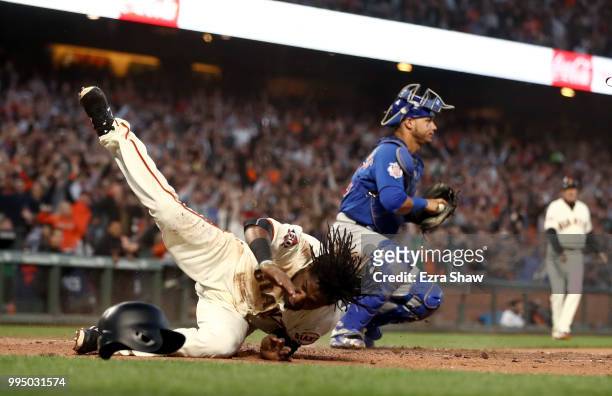 Alen Hanson of the San Francisco Giants beats the tag of Willson Contreras of the Chicago Cubs to score after a failed pick off attempt in the fifth...