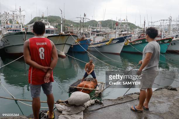Fisherman navigates a raft near boats filling the Patoutzu Fishing Harbour in Keelung on July 10 as Typhoon Maria approaches northern Taiwan. -...