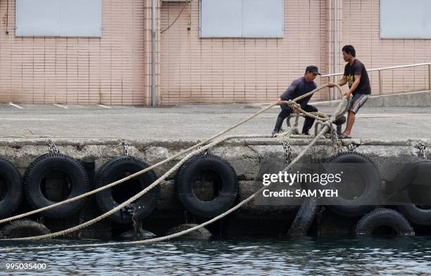 Workers secure a rope to the shore at the Patoutzu Fishing Harbour in Keelung on July 10 as boats come into dock ahead of the arrival of Typhoon...