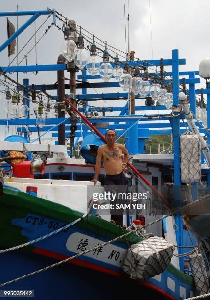 Fishing boat owner stands on the deck of his vessel as it sits docked at the Patoutzu Fishing Harbour in Keelung on July 10 as Typhoon Maria...