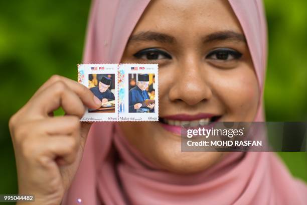 Postal worker Nurshafiqa Kasim poses with limited edition postage stamps depicting Malaysia's Prime Minister Mahathir Mohamad during his 93rd...