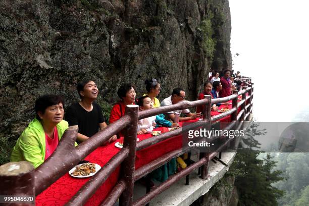 This photo taken on July 8, 2018 shows tourists during a banquet held along the edge of a cliff, at Laojun Mountain in Luoyang in China's central...