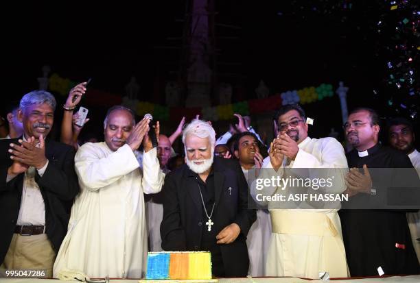 Newly-appointed Pakistani Cardinal Joseph Coutts cuts a cake during a welcoming ceremony at Saint Patrick Church in Karachi on July 10 after his...