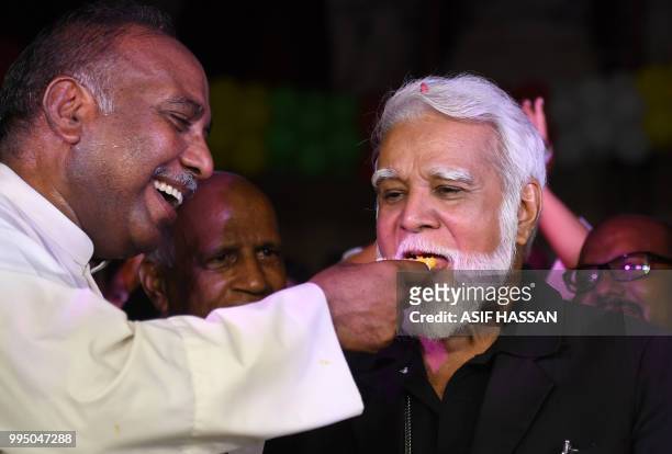 Pakistani Roman Catholic priest offers sweet to the newly-appointed Pakistani Cardinal Joseph Coutts during a welcoming ceremony at Saint Patrick...