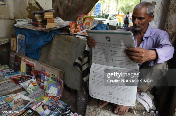 This photo illustration shows an Indian newspaper vendor reading a newspaper with a full back page advertisement from WhatsApp intended to counter...