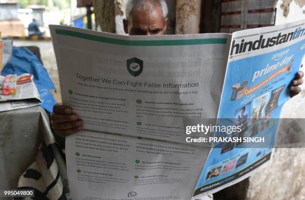 This photo illustration shows an Indian newspaper vendor reading a newspaper with a full back page advertisement from WhatsApp intended to counter...