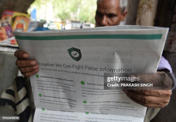 This photo illustration shows an Indian newspaper vendor reading a newspaper with a full back page advertisement from WhatsApp intended to counter...