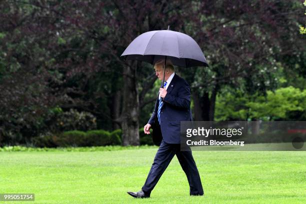President Donald Trump carries an umbrella while walking towards Marine One to depart from the White House in Washington, D.C., U.S., on Wednesday,...